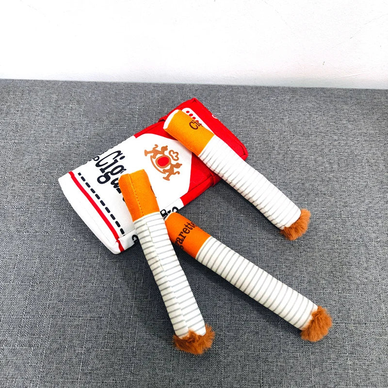 Paquet de cigarettes en peluche pour chien posé sur un canapé avec trois cigarettes
