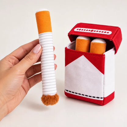Cigarette en peluche pour chien tenue en main à côté du paquet ouvert, pour montrer sa taille réelle